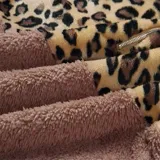 Buzo tipo canguro de polar, con diseño combinado en animal print de leopardo en la parte superior y color gris claro en la parte inferior. Cuenta con capucha, cordones ajustables y cierre frontal.