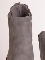 Bota tipo chelsea de cuero sintético color marrón, con paneles laterales elásticos y suela de goma blanca con relieve dentado.