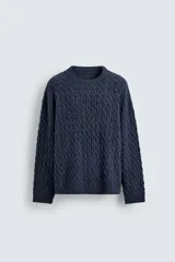 Jersey de punto con diseño de trenzas, cuello redondo y manga larga. Presenta un ajuste oversized y acabados en rib en puños y ruedo.