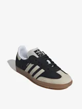 Zapatillas Adidas Samba OG, color negro con las tres tiras laterales en blanco y suela de goma marrón.