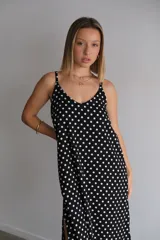 Vestido largo de crepe con estampado de lunares negros sobre fondo blanco. Presenta un diseño de corte holgado con breteles finos y escote redondeado.