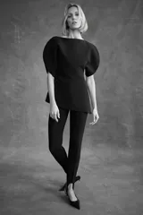 Top color crema de cuello redondo y manga corta abullonada. Presenta un bajo asimétrico y cierre en la espalda con cremallera oculta en la costura.