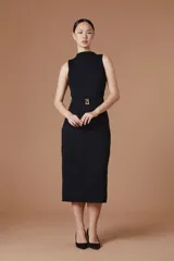 Vestido midi sin mangas, de cuello alto y textura plisada con ondas verticales. Presenta un corte entallado con un cinturón negro integrado que incluye una hebilla metálica dorada con el logo de la marca.