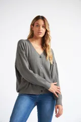 Cárdigan de tejido liviano con textura acanalada, cuello en V y cierre frontal con botones. Presenta mangas largas y un diseño clásico con detalle de grifa en cuero.