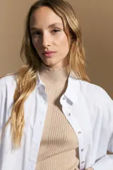 Polera de tejido acanalado con cuello alto, corte ajustado al cuerpo y mangas tres cuartos con terminaciones onduladas en los puños.