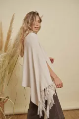 Poncho tejido de punto acanalado en color marrón chocolate, con cuello alto y diseño irregular con flecos en los bordes.