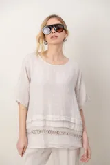 Blusa de lino color blanco, de corte amplio, con escote redondo, mangas cortas y detalle de guarda calada horizontal en la parte inferior.