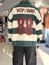 Buzo polo de rayas horizontales en verde oscuro y beige, con cuello alto, cierre frontal parcial y manga larga. Presenta detalles estampados en la espalda con el texto 'VCP/ARG' y el número '88'.
