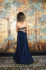 Vestido largo strapless de encaje negro con transparencias y espalda descubierta con tiras cruzadas, de corte entallado y falda de caída suelta.