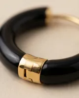 Aros tipo argolla de tamaño pequeño, con diseño minimalista en color negro brillante y detalle metálico en el cierre.