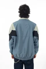 Campera deportiva azul con recortes en negro y verde agua, cierre frontal con cremallera y cuello tipo mao.