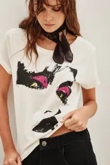 Remera de algodón color crudo con estampa frontal gráfica de estilo pixelado que representa un rostro con detalles en fucsia y amarillo.