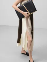 Clutch negro de piel bovina con estructura de lienzos superpuestos y cierre de solapa.