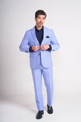 Traje de lino color beige claro, compuesto por saco de dos botones con solapa de muesca, dos bolsillos delanteros con solapa y un bolsillo en el pecho, y pantalón de vestir de corte recto. Incluye camisa blanca, corbata estampada y zapatos marrones.