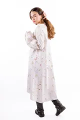 Vestido midi de algodón con silueta amplia y holgada. Presenta mangas largas con volumen y puños ajustados. El diseño destaca por su estampado artesanal con motivos orgánicos en tonos tierra y toques rojizos sobre base blanca.
