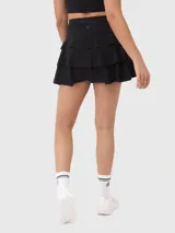 Falda deportiva negra con calza interior, de corte acampanado con vuelos en la parte trasera. Cuenta con un pequeño bolsillo con cierre en la pretina y otro bolsillo en el interior de la calza.