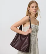 Cartera hobo grande de poliuretano color marrón, con diseño estructurado, asa única larga y base reforzada.