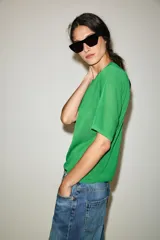 Chaqueta de punto de manga corta y cuello redondo en color verde, con cierre frontal de botones.