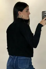 Buzo de hilo de punto con diseño de trenzas verticales, cuello alto y cadena metálica decorativa incorporada en la parte frontal.