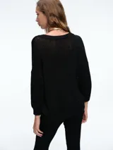 Sweater de punto con brillo, de corte relajado y escote en V. Presenta hombros caídos y mangas largas con puños acanalados.