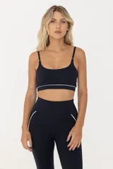 Top deportivo negro con breteles finos regulables y contorno inferior blanco.