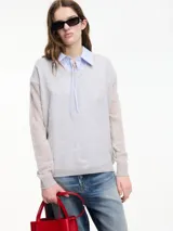 Sweater de punto fino color gris claro, con cuello en V y mangas largas. El tejido parece ser ligeramente transparente o muy liviano.