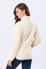 Campera de sherpa color beige con cuello alto y cierre frontal. Presenta un bolsillo frontal en el pecho de gamuza color arena con cierre y etiqueta decorativa, además de detalles en gamuza en los bordes.