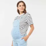 Enterito de jean celeste claro, estilo peto o jardinero, con panel elástico para maternidad sobre el abdomen. El corte de las piernas es recto y holgado.