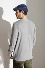 Remera de manga larga gris de tejido waffle, con cuello redondo y cierre frontal parcial de tres botones.