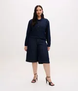 Campera cropped de jean color azul oscuro, con cuello camisero, cierre frontal de botones metálicos, bolsillos frontales grandes con solapa y mangas largas.