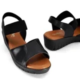 Sandalias de cuero negro con plataforma baja y elástico en el tobillo.