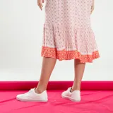 Vestido midi de corte recto, con estampado floral en tonos rosa y naranja sobre fondo crudo. Presenta cuello en V, mangas cortas y ruedo con volantes.