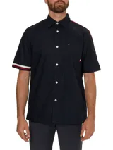 Camisa de manga corta azul marino con cierre de botones, bolsillo en el pecho y rayas rojas y blancas en los hombros.