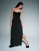 Vestido largo negro de corte recto con breteles finos. Presenta un detalle de frunce en el busto con aplicación de lentejuelas y un tajo lateral en la falda.