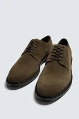 Zapato tipo derby con cordones, confeccionado en piel con acabado de serraje. Presenta horma redonda y suela a contraste.