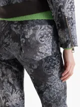 Pantalón de gabardina con corte jeanero y estampado damasco en tonos grises. Presenta bolsillos delanteros curvos con bolsillo relojero, bolsillos traseros plaqué y cierre frontal con broche metálico.