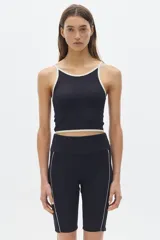 Top deportivo corto negro con cuello halter y tirantes finos en color crema.