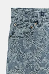 Pantalón jean tiro alto de corte flare con diseño jacquard estampado completo, cinco bolsillos, trabillas para cinto y cierre frontal con cremallera y botón metálico.