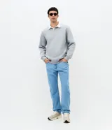 Pantalón de jean color azul claro, con corte recto, diseño clásico de cinco bolsillos, cierre frontal con botón y cremallera, y presillas para cinturón.