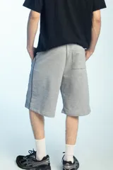 Bermuda deportiva de felpa color negro, de corte ancho y largo por debajo de las rodillas, con cintura elástica.