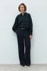 Camisa de manga larga con estampado de cuadros en tonos verde y azul marino, cuello clásico y cierre frontal con botones.