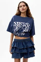 Remera oversized de algodón color azul, con hombros caídos, cuello redondo y estampa gráfica frontal de estilo artístico en tono claro.