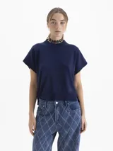 Chaleco de tejido de punto en color celeste, con cuello redondo y mangas cortas con terminación en rib. Presenta un diseño holgado con aberturas laterales en el ruedo y un pequeño bordado decorativo en la parte inferior.