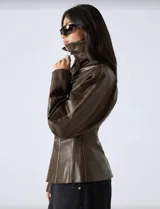 Chaqueta de efecto cuero en color marrón chocolate, con silueta entallada, cierre frontal con cremallera, cuello amplio y mangas con volumen.