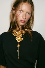 Collar doble de cadena metálica dorada con diseño de flores en relieve y hojas, con caída larga y detalles florales en los extremos.