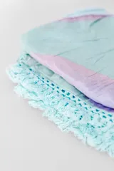 Pareo de playa blanco con estampado de hojas verdes y borde de encaje con flecos.