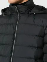 Campera puffer negra con capucha, cierre frontal con cremallera plateada y bolsillos laterales con cierre. Es reversible y está rellena de plumas.