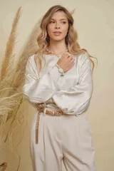 Blusa de satén color beige, con cuello a la base, mangas anchas abullonadas y puños elásticos bordados.