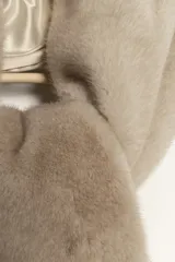 Bufanda de piel sintética color marrón oscuro, con forro interior de satén liso del mismo tono. Presenta un diseño con una abertura central para pasar un extremo y asegurar la bufanda al cuello.