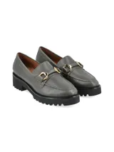 Mocasín de cuero color verde militar con suela track negra y detalle de herraje metálico dorado en el empeine.